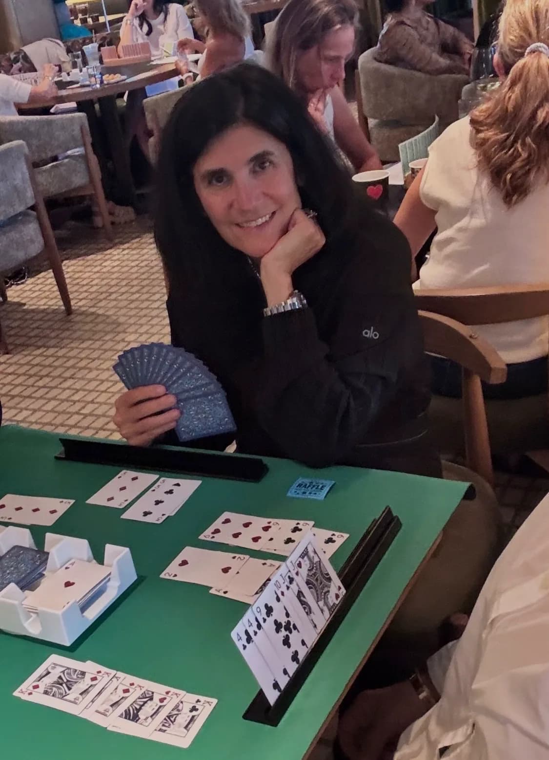 A player at the Canasta Chicago Club table holding a hand of cards